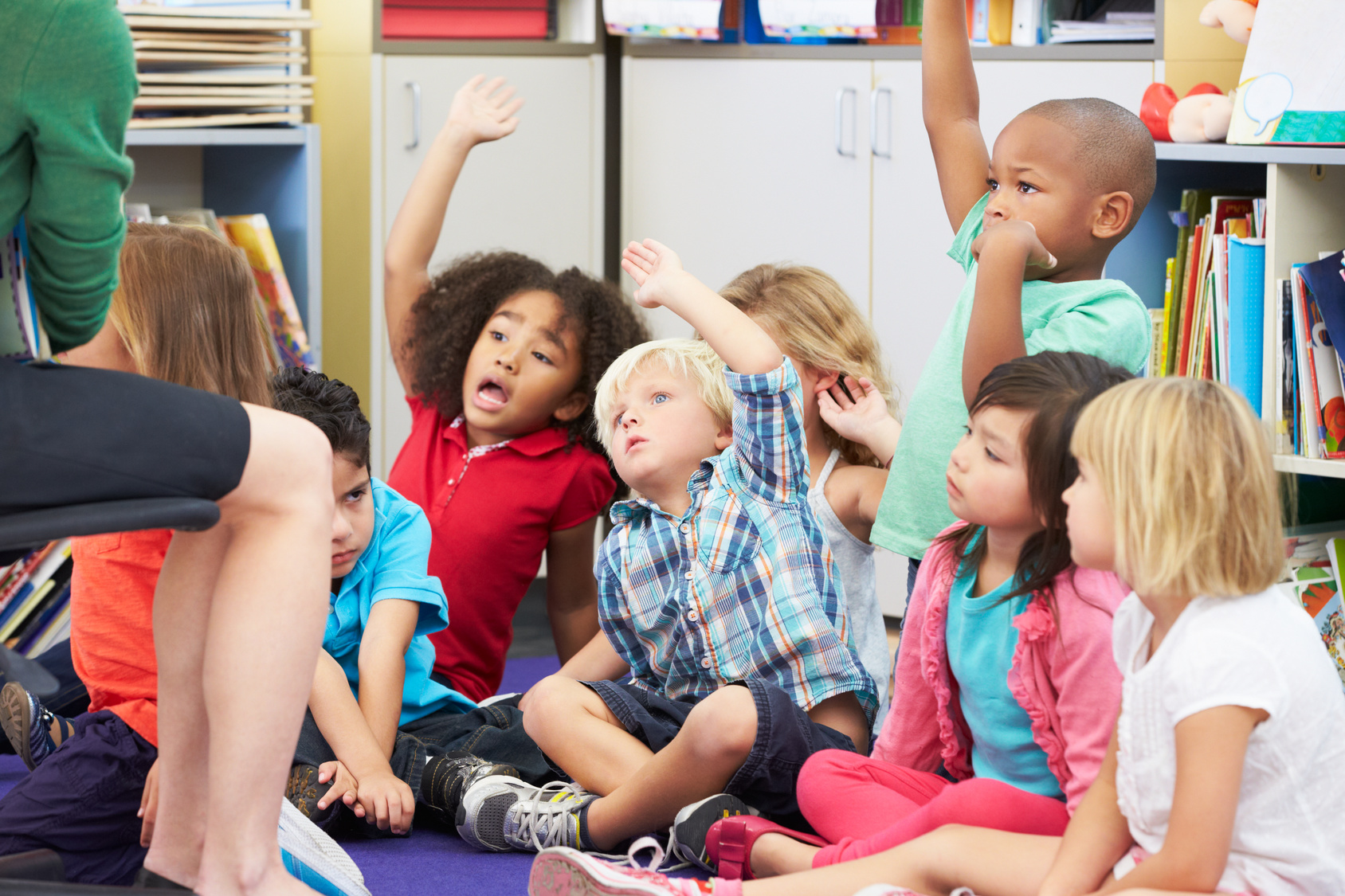 preschool children raising hands on rug